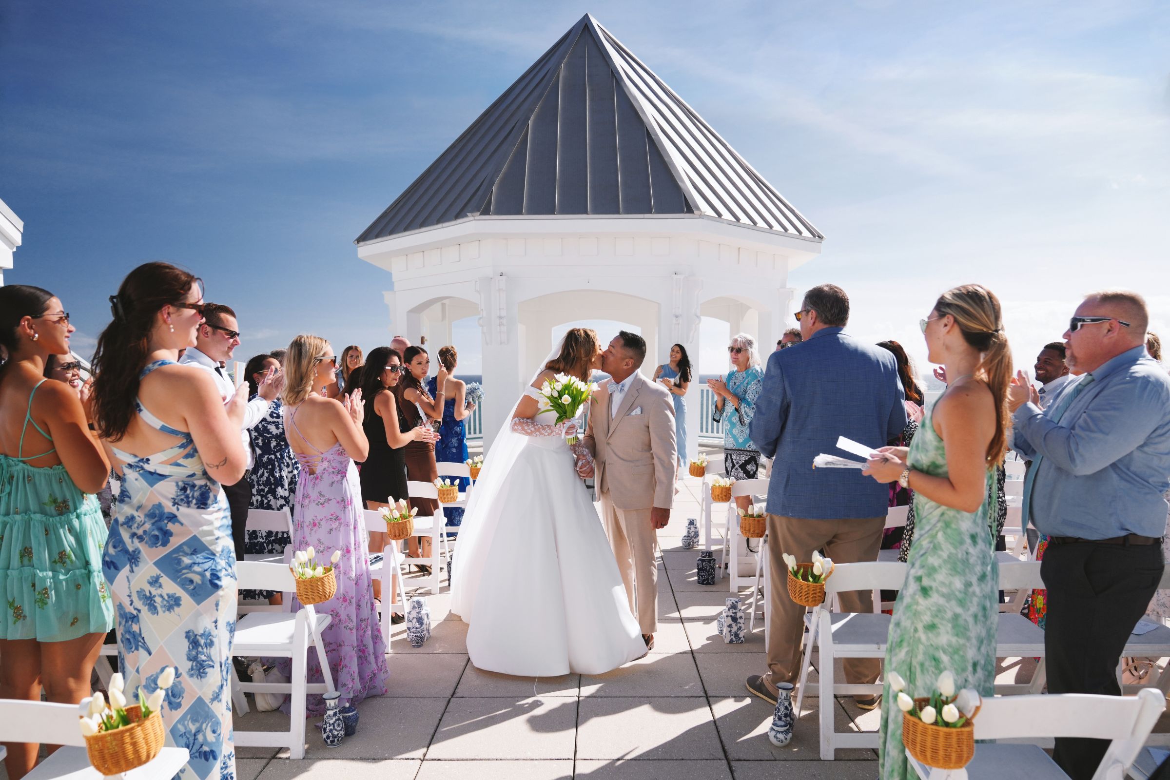 Bride and groom kissing after saying vows with the ocean in the background.