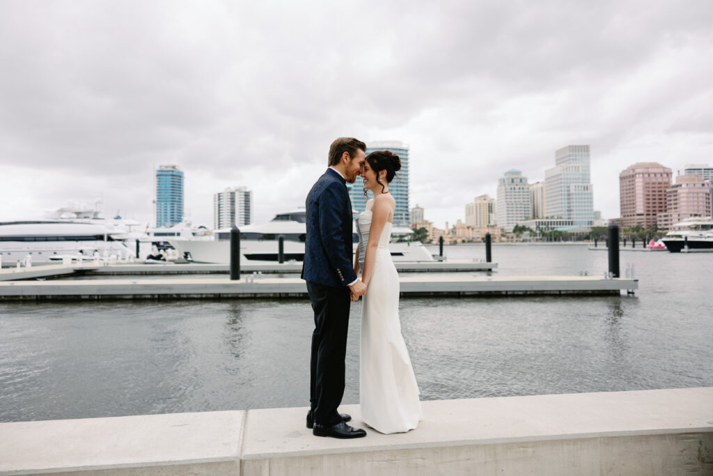 bride and groom facing each other by water