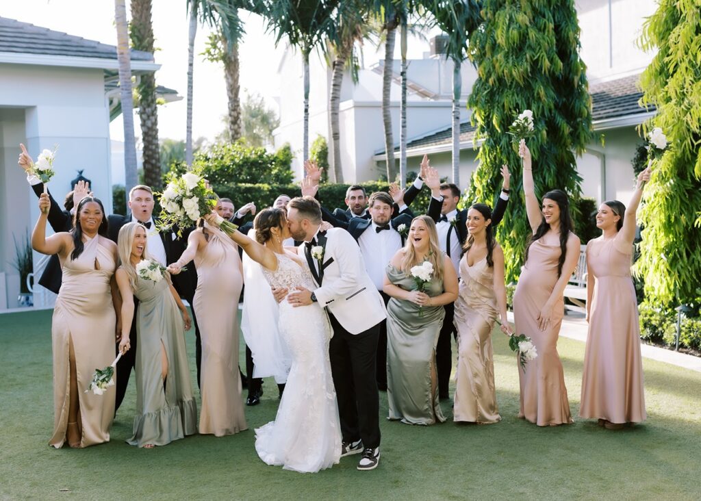 Bridal Party celebrating behind the bride and groom kissing