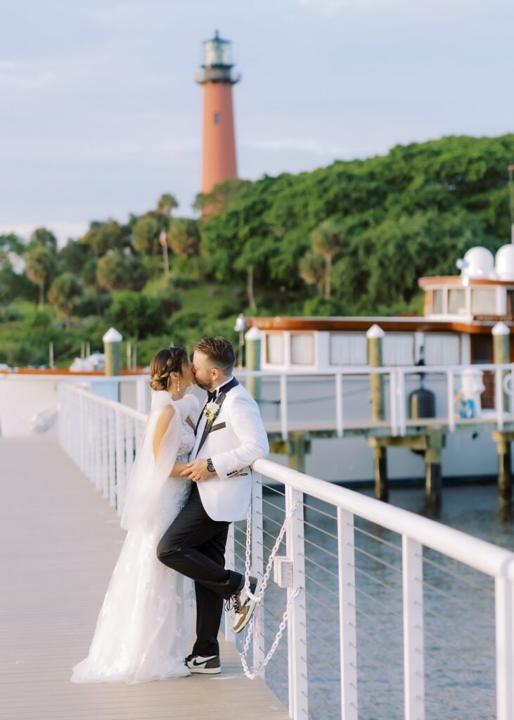 Bride and groom sharing a kiss on the dock with overlooking the Jupiter Inlet Lighthouse