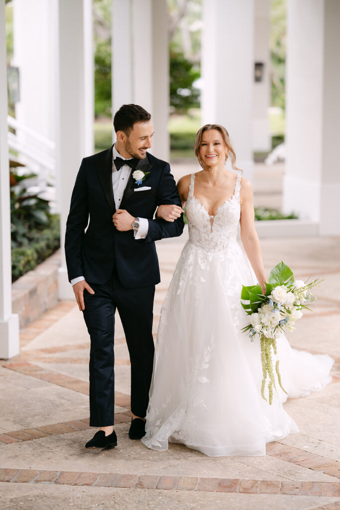 Bride and groom walking arm and arm down the walkway at Pelican Club South Florida