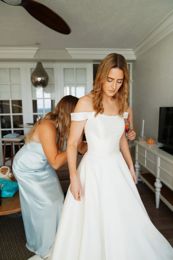 Bride putting on her wedding gown with her bridesmaids